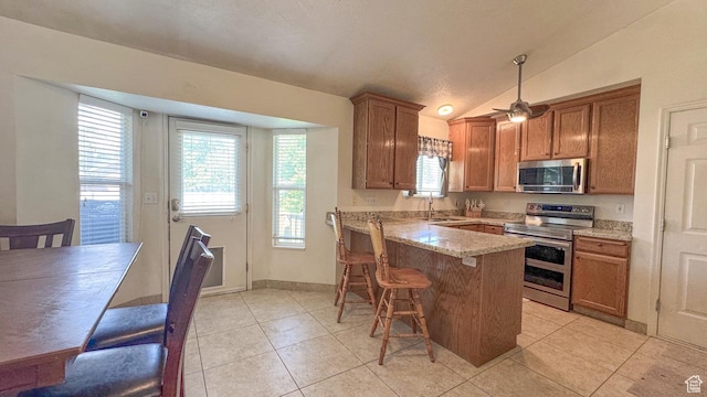 1447 E 230 S, Spanish Fork, UT 84660 - kitchen featuring stainless steel appliances, a peninsula, light tile patterned flooring, lofted ceiling, and a breakfast bar