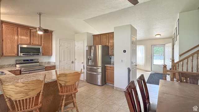 1447 E 230 S, Spanish Fork, UT 84660 - kitchen with appliances with stainless steel finishes, a ceiling fan, brown cabinetry, light tile patterned flooring, and lofted ceiling