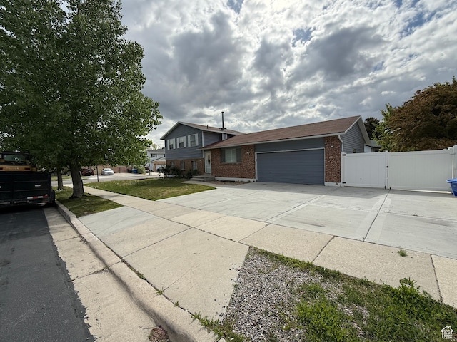 6351 S Moki Cir W, West Jordan, UT 84081 - tri-level home featuring brick siding, an attached garage, a gate, concrete driveway, and fence