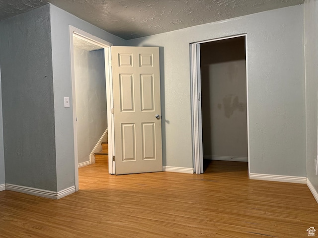 6351 S Moki Cir W, West Jordan, UT 84081 - unfurnished bedroom featuring light wood-style floors, baseboards, a closet, a textured wall, and a textured ceiling