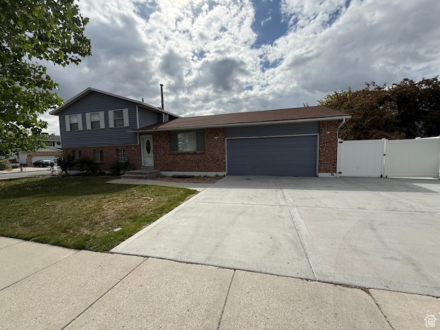 6351 S Moki Cir W, West Jordan, UT 84081 - split level home with brick siding, an attached garage, driveway, and a gate