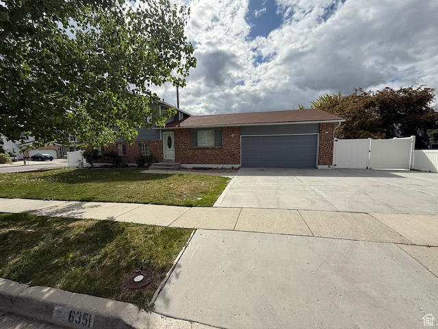 6351 S Moki Cir W, West Jordan, UT 84081 - split level home featuring a gate, brick siding, an attached garage, and driveway