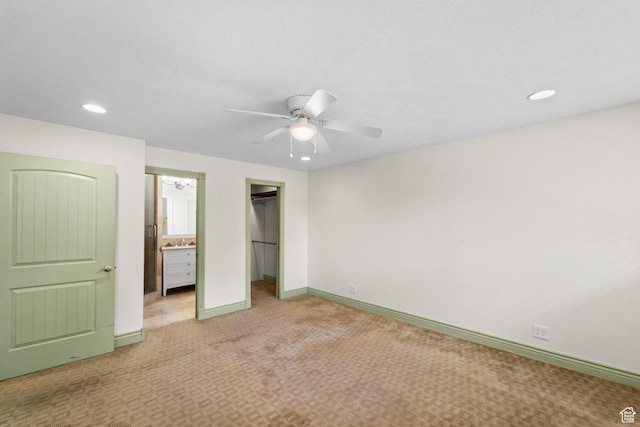 unfurnished bedroom with light colored carpet, recessed lighting, baseboards, a walk in closet, and a closet