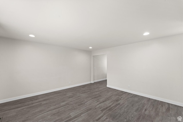 empty room with recessed lighting, dark wood finished floors, and baseboards