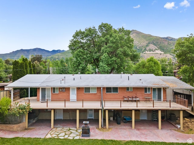 back of house with a patio area, central air condition unit, and a deck with mountain view