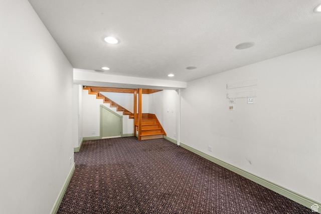 finished below grade area with stairs, dark carpet, recessed lighting, and baseboards