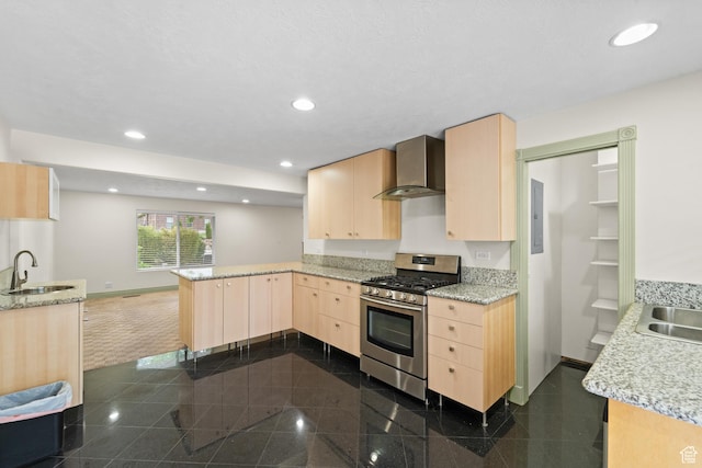 kitchen featuring stainless steel range with gas cooktop, light brown cabinets, wall chimney range hood, a peninsula, and granite floors