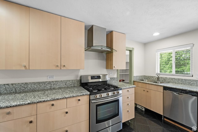 kitchen featuring appliances with stainless steel finishes, wall chimney exhaust hood, light brown cabinetry, a sink, and granite floors
