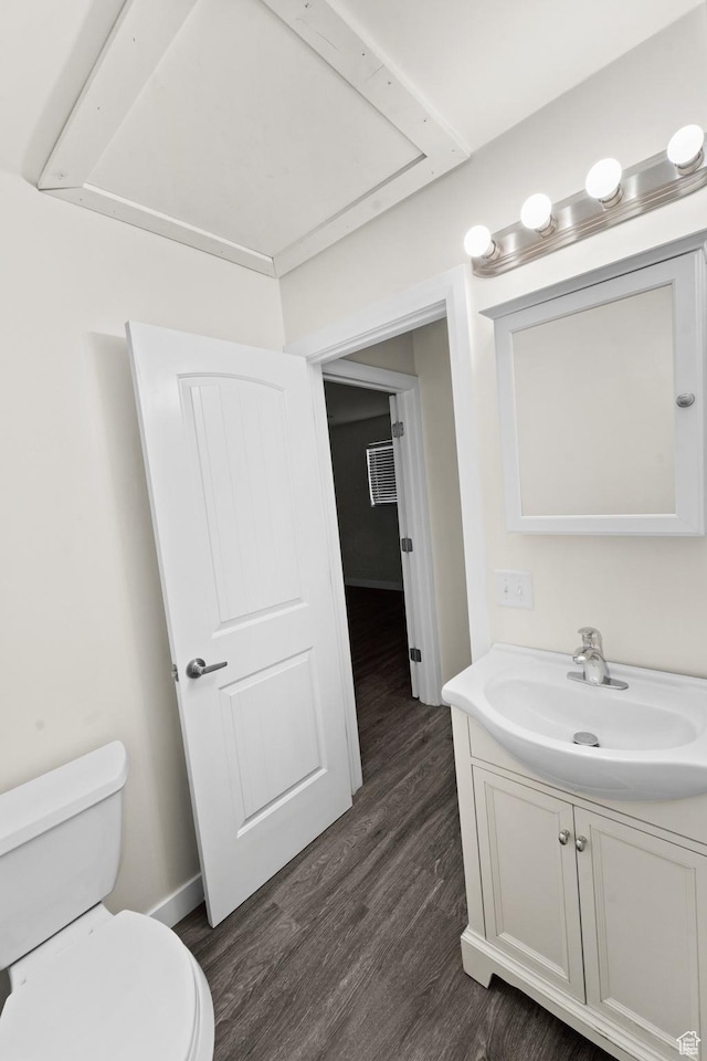 bathroom with toilet, vanity, wood finished floors, and baseboards