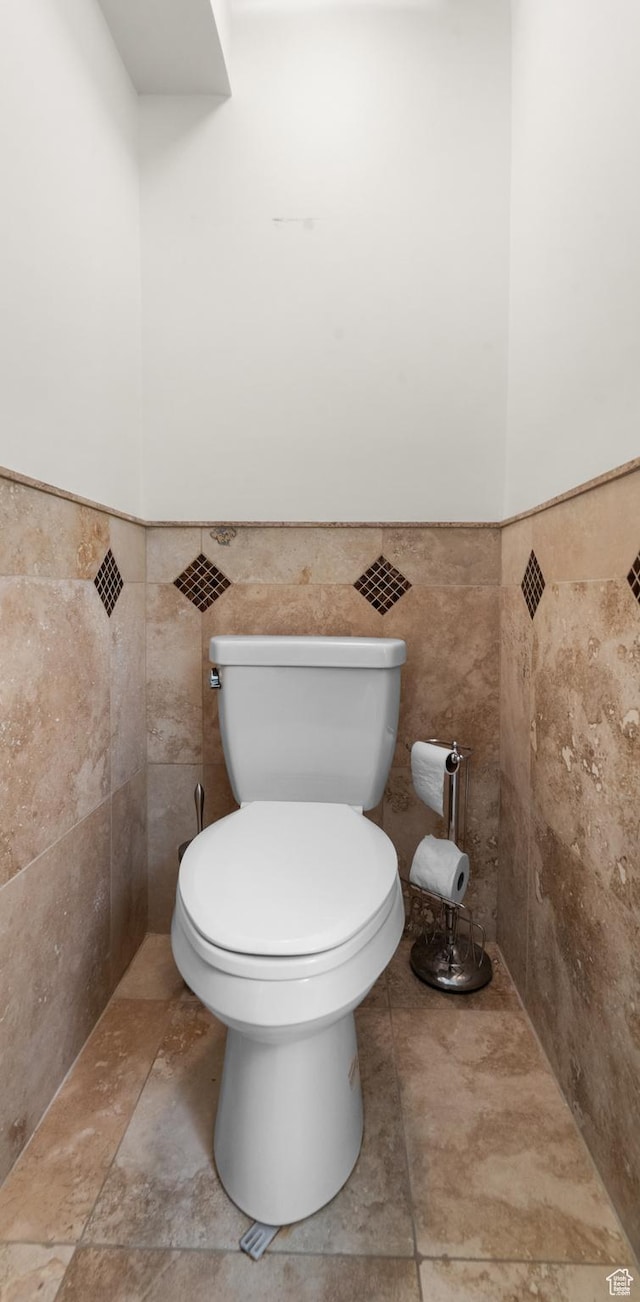 bathroom featuring toilet, tile walls, and a wainscoted wall