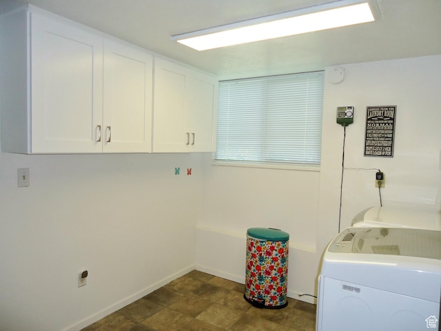 clothes washing area featuring cabinet space and baseboards