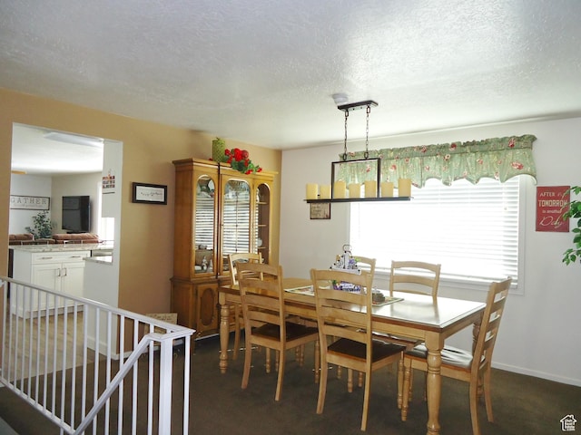 dining area with a textured ceiling and dark carpet