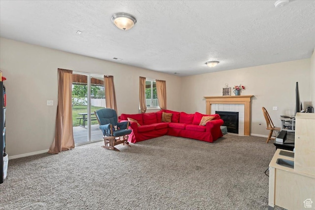 carpeted living room featuring a tiled fireplace, a textured ceiling, and baseboards