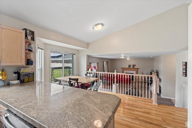 kitchen featuring light brown cabinetry, light wood finished floors, open shelves, a peninsula, and lofted ceiling