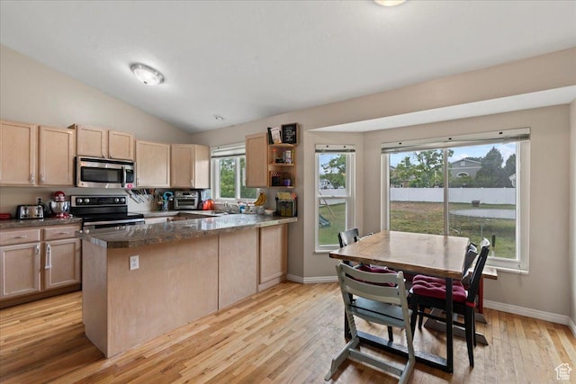 kitchen with stainless steel appliances, light brown cabinets, a peninsula, light wood-style floors, and a sink