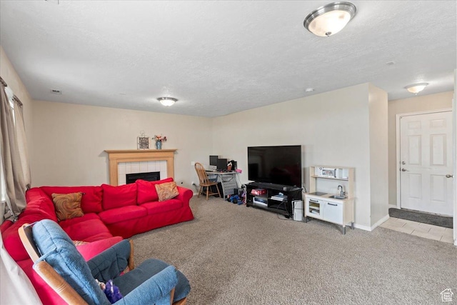living room featuring carpet, a textured ceiling, and a tile fireplace