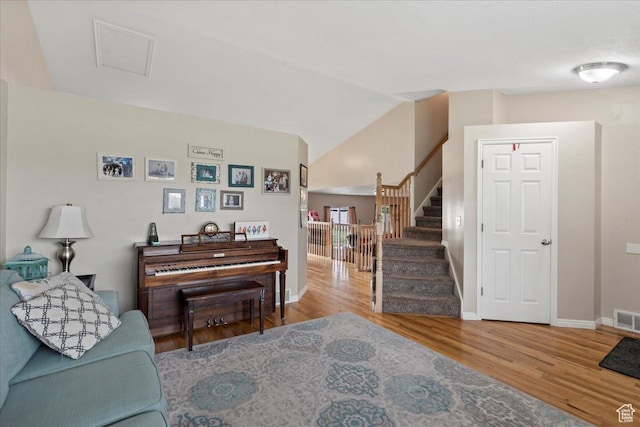 living room with wood finished floors, stairs, baseboards, and vaulted ceiling