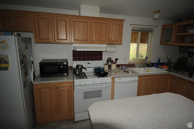 kitchen featuring white appliances, under cabinet range hood, a sink, brown cabinets, and light countertops