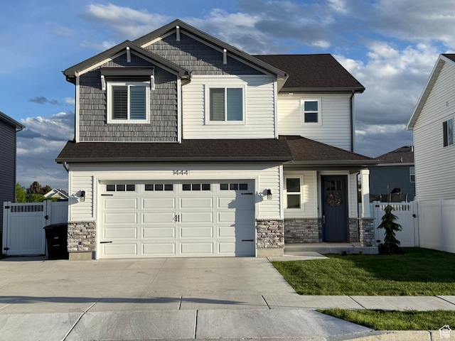 craftsman-style home with a gate, concrete driveway, a garage, stone siding, and roof with shingles