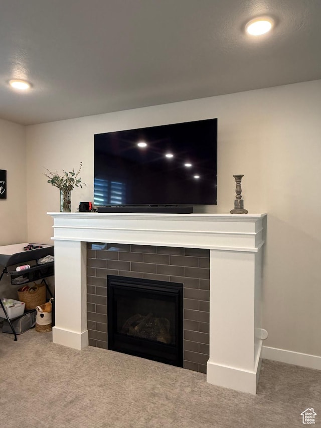 detailed view of a tile fireplace, carpet flooring, and baseboards
