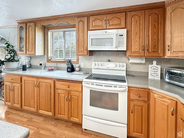 415 N Cedar Vw, Orangeville, UT 84537 - kitchen featuring white appliances, decorative backsplash, light wood-type flooring, brown cabinets, and a textured ceiling