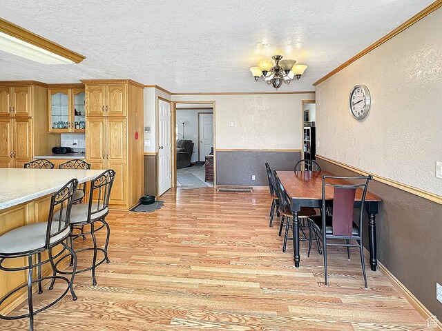 415 N Cedar Vw, Orangeville, UT 84537 - dining area featuring a textured wall, a chandelier, light wood-style flooring, a textured ceiling, and crown molding