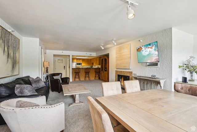 carpeted living room featuring rail lighting and a glass covered fireplace