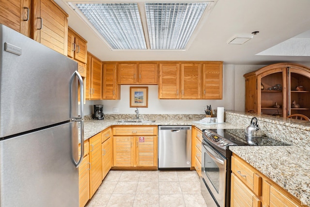 kitchen with appliances with stainless steel finishes, a sink, and light tile patterned floors