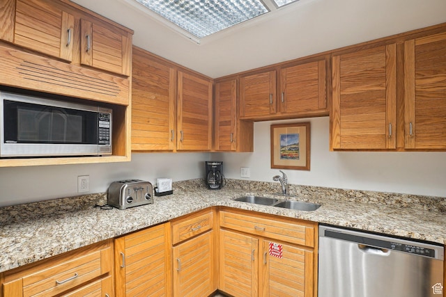 kitchen featuring stainless steel appliances, a sink, and light stone counters