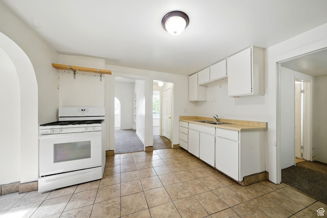 653 E Hollywood Ave, Salt Lake City, UT 84105 - kitchen featuring white gas range oven, arched walkways, a sink, and light countertops
