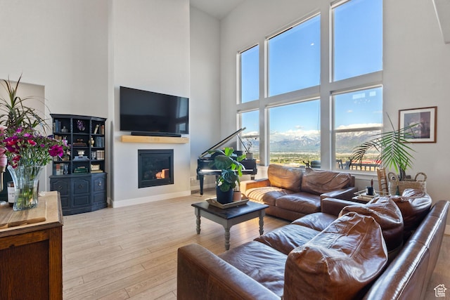 14949 S Billings Dr W Unit 119, Herriman, UT 84096 - living room with a high ceiling, a glass covered fireplace, wood-type flooring, and baseboards