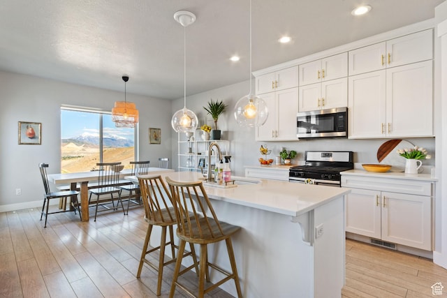 14949 S Billings Dr W Unit 119, Herriman, UT 84096 - kitchen featuring stainless steel appliances, a sink, light wood finished floors, light countertops, and a kitchen island with sink