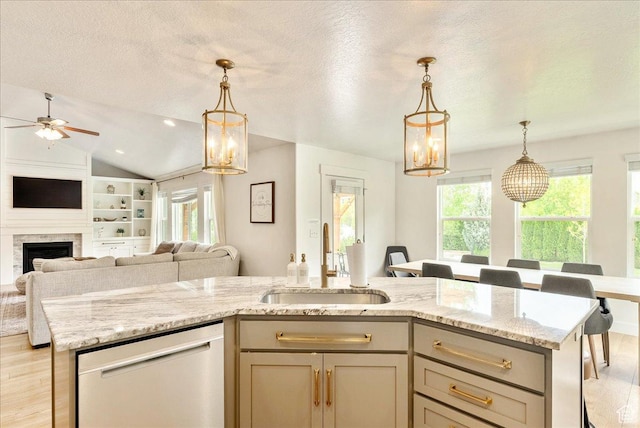 kitchen with dishwasher, a sink, open floor plan, light wood-style floors, and a textured ceiling