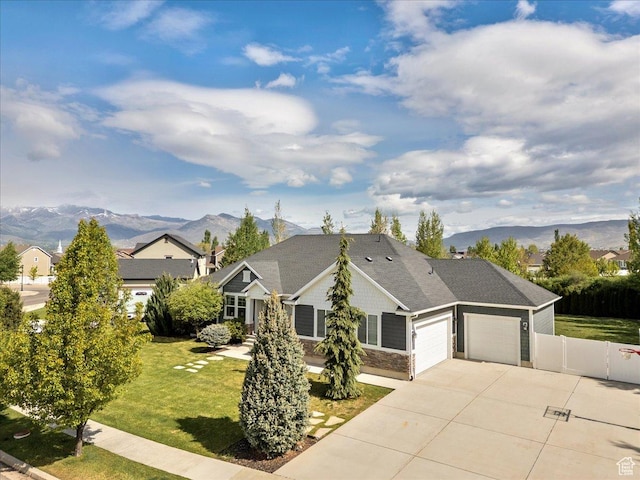view of front of home featuring an attached garage, a mountain view, stone siding, and driveway