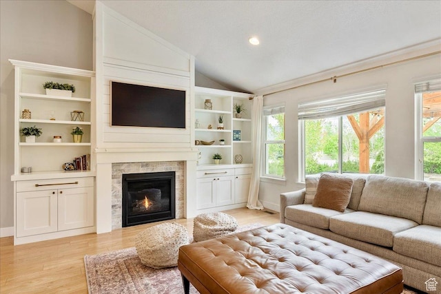 living room with light wood-type flooring, a tile fireplace, vaulted ceiling, and recessed lighting