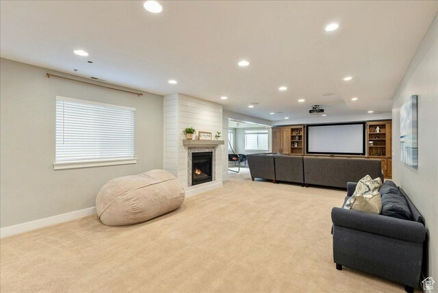 living area featuring recessed lighting, light carpet, baseboards, and a warm lit fireplace