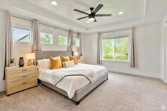 bedroom with a tray ceiling, light carpet, baseboards, recessed lighting, and ceiling fan