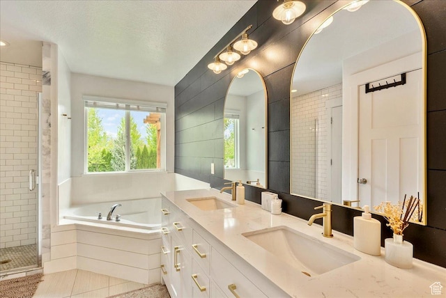 bathroom featuring healthy amount of natural light, a shower stall, a bath, double vanity, and a textured ceiling