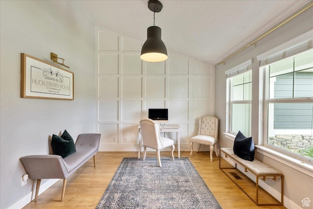 living area with lofted ceiling, a desk, light wood finished floors, and baseboards