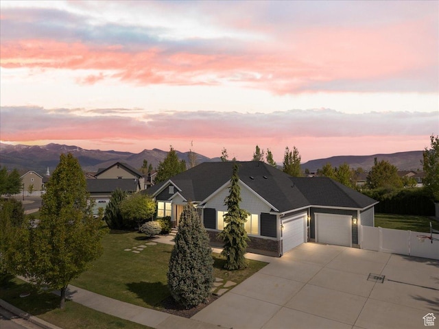 view of front of home featuring a garage, driveway, stone siding, and a mountain view