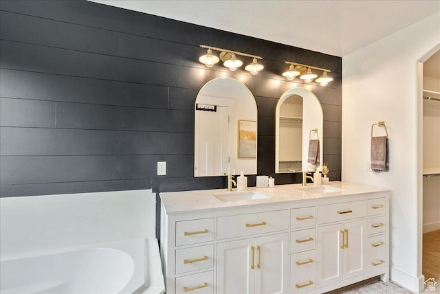 bathroom with double vanity, a bath, and a spacious closet