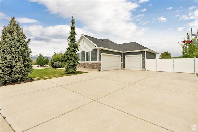 view of side of property with a garage, driveway, and stone siding