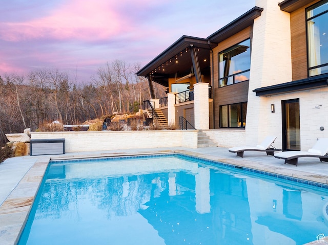 outdoor pool featuring stairs and a patio area