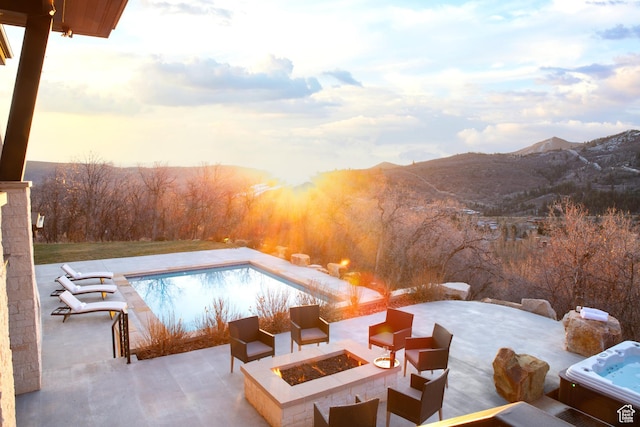 swimming pool with an outdoor fire pit, a patio, a mountain view, and a hot tub