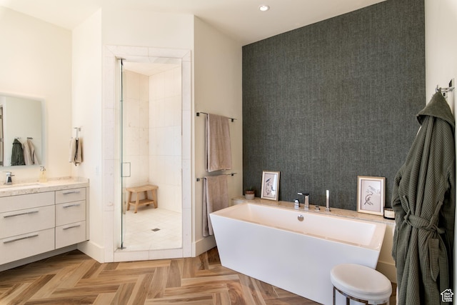 bathroom featuring a stall shower, a freestanding bath, recessed lighting, vanity, and an accent wall