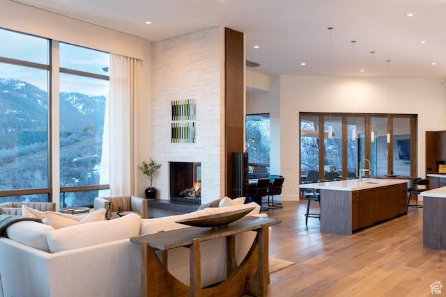 living room with a fireplace, light wood-style flooring, a mountain view, plenty of natural light, and recessed lighting