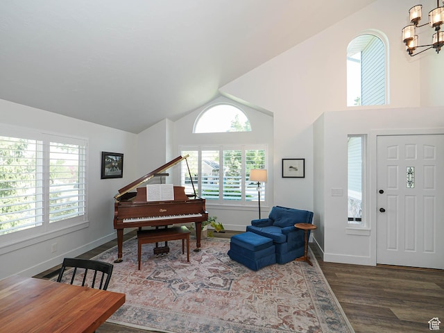 sitting room with a chandelier, wood finished floors, baseboards, and high vaulted ceiling