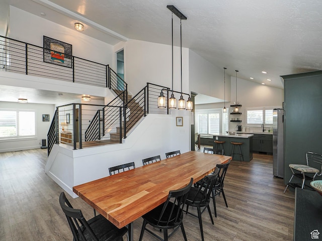 dining room with stairway, dark wood-type flooring, high vaulted ceiling, and recessed lighting