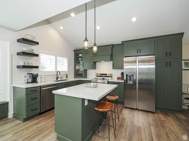 kitchen with green cabinets, appliances with stainless steel finishes, a sink, open shelves, and light wood-type flooring