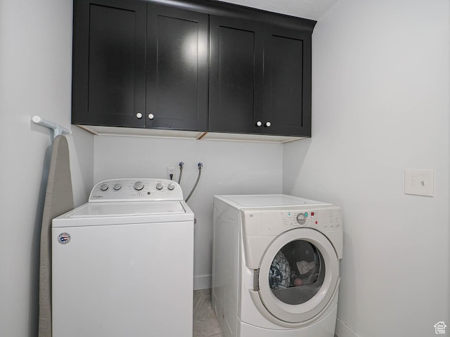 washroom with cabinet space, washing machine and clothes dryer, and baseboards